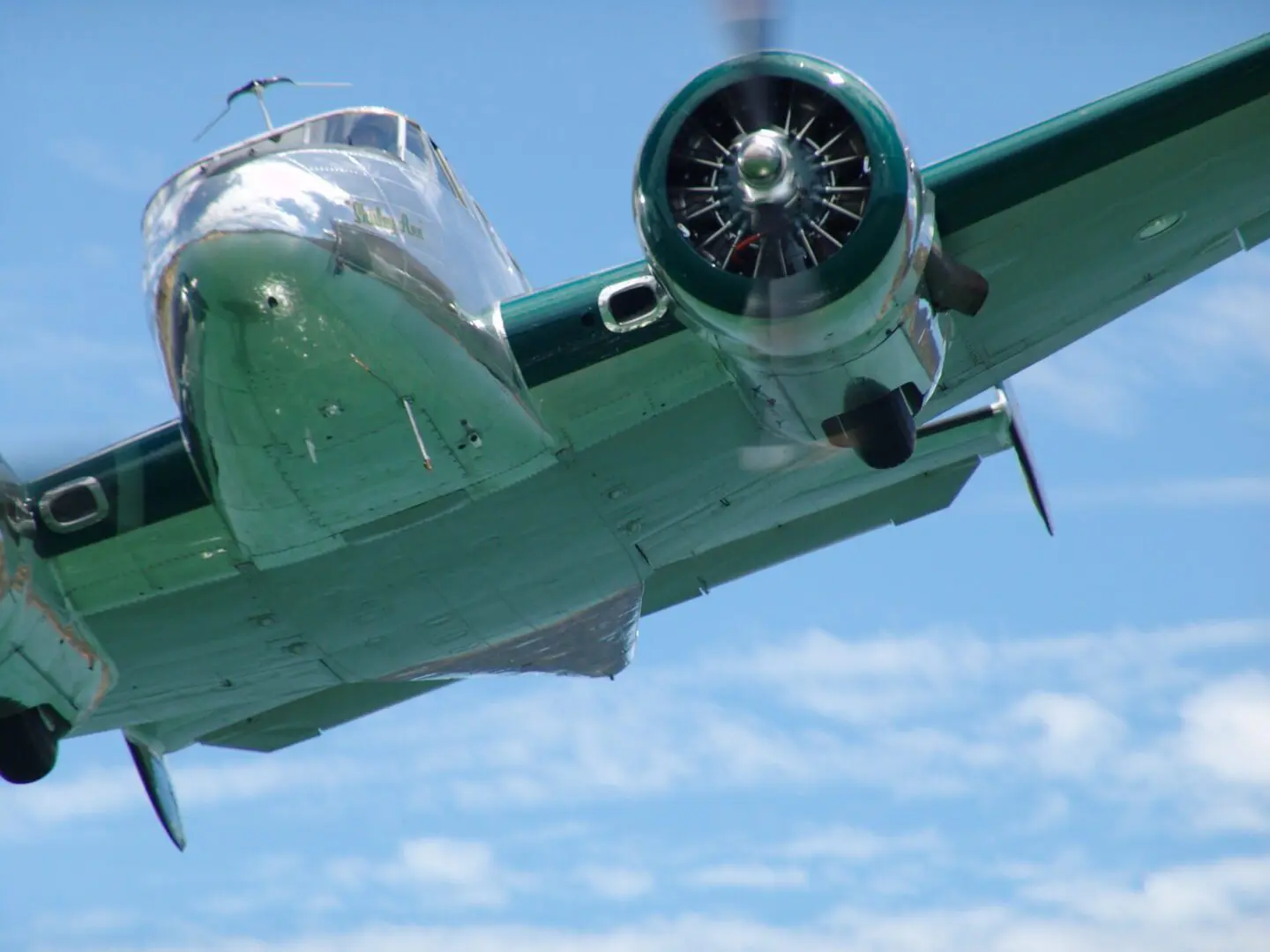 A vintage twin-engine airplane flying against a blue sky.