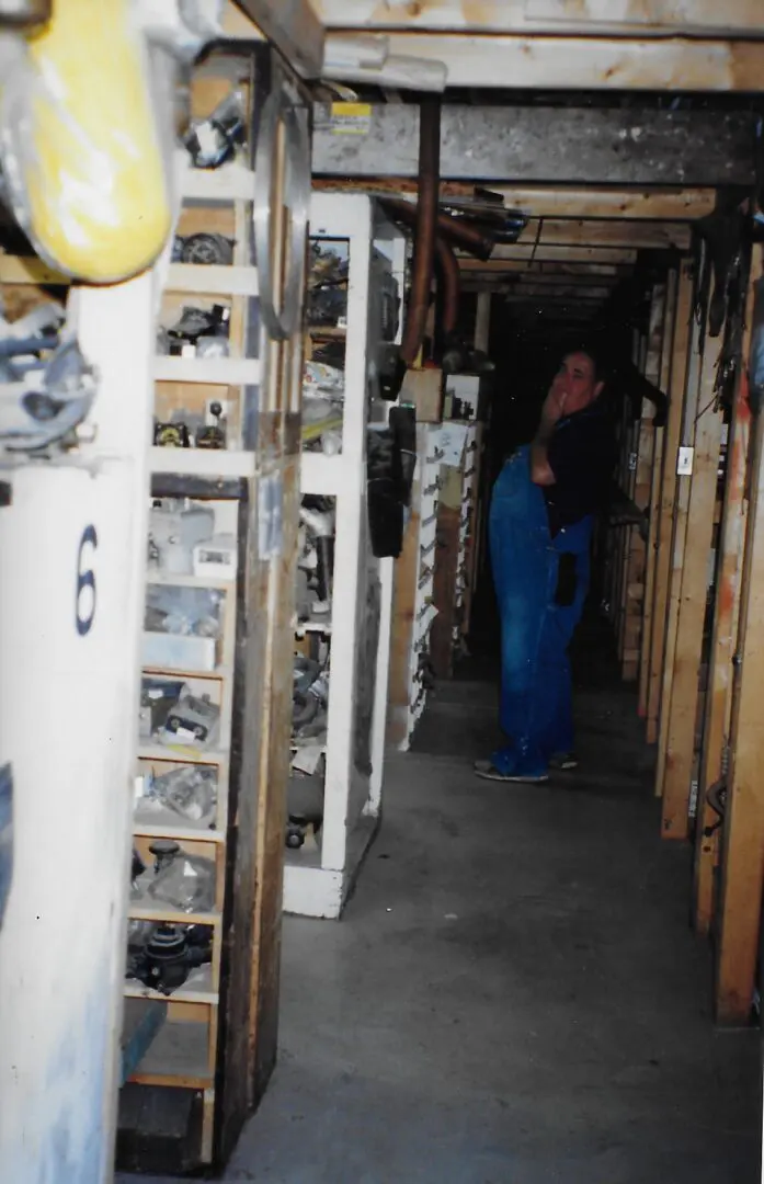 Person walking through a narrow, cluttered storage corridor.