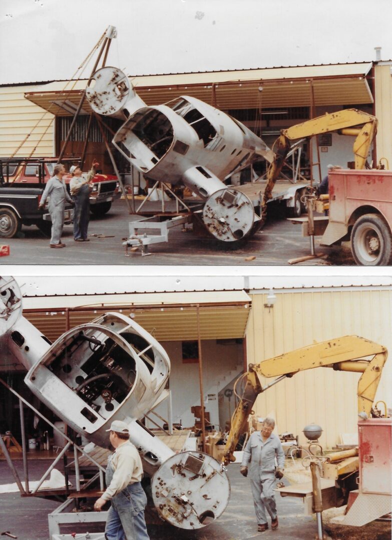 Car crash wreckage lifted by heavy machinery at a roadside scene.